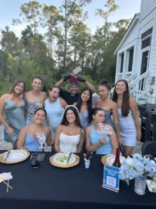 Bride and bridesmaids smiling at hibachi dinner table with private chef holding spatula