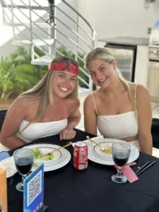 Two smiling women at a private hibachi dinner, wearing white outfits and enjoying the moment