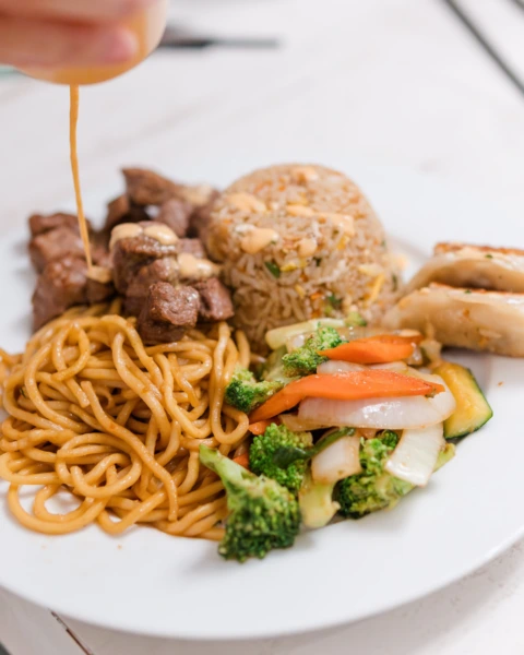 Hibachi meal with noodles, steak, fried rice, veggies, and sauce drizzle – MyHibachiAtHome