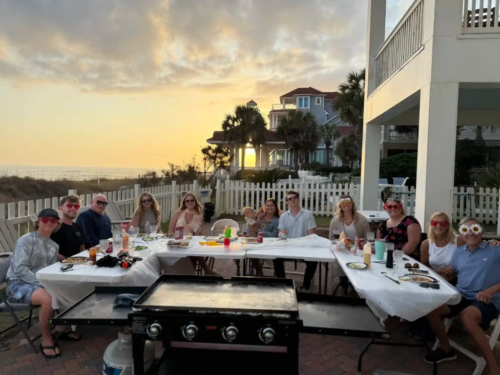 Guests enjoying hibachi catering with sunset view at a beach house rental